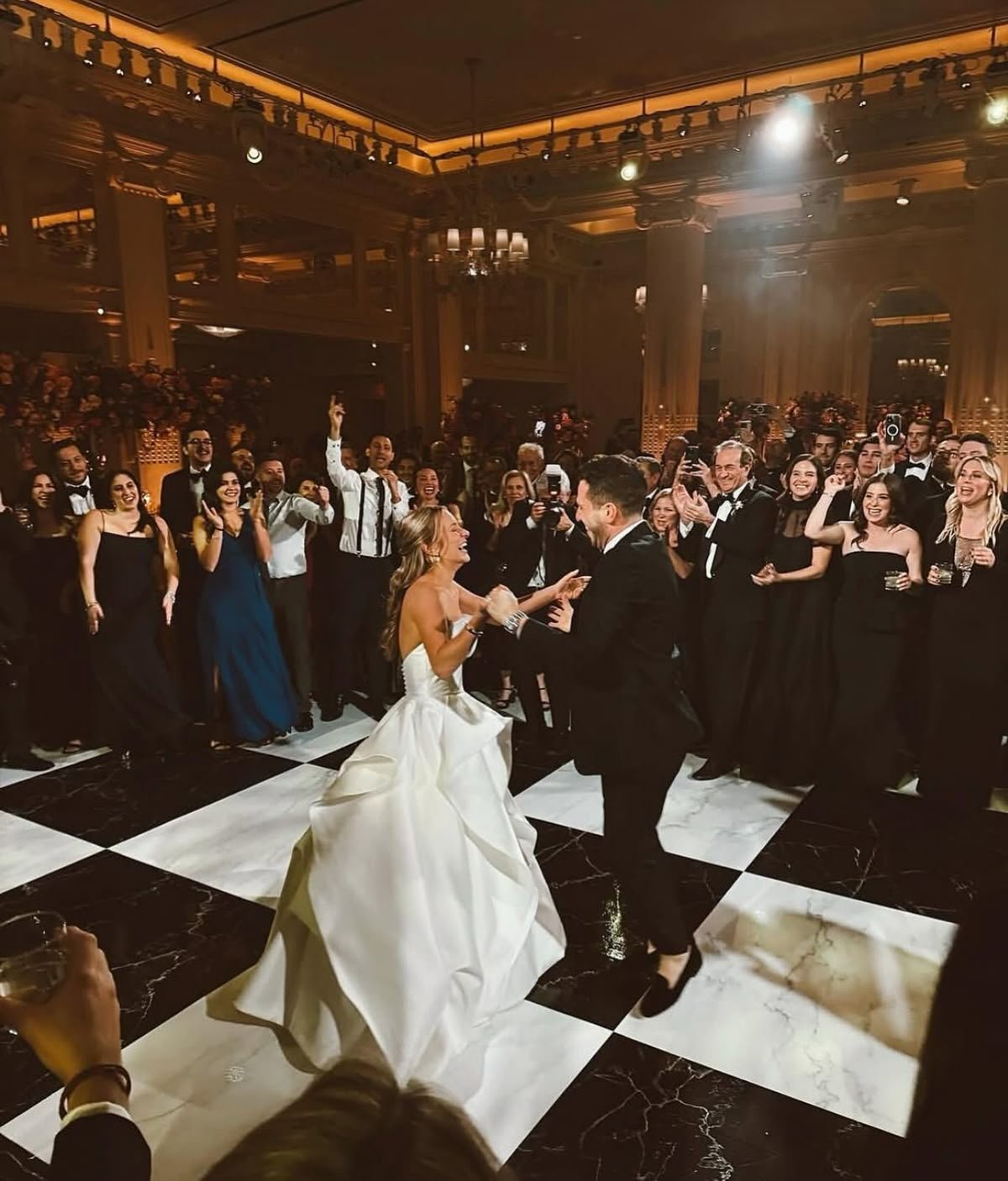 Guests cheering around a couple dancing on a black and white checkered marble style floor at a Los Angeles wedding reception
