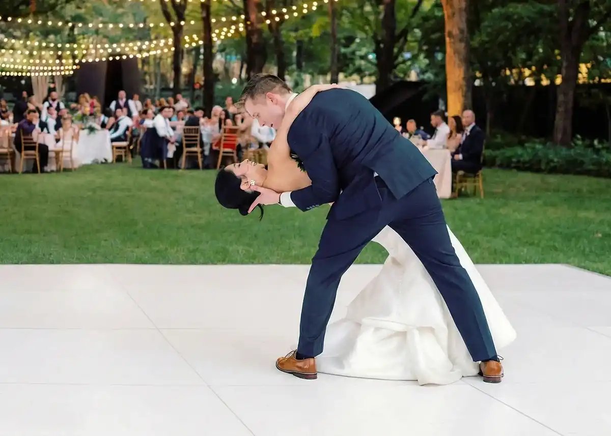 Bride and groom sharing a dip during their first dance on a white dance floor at an outdoor Los Angeles wedding reception